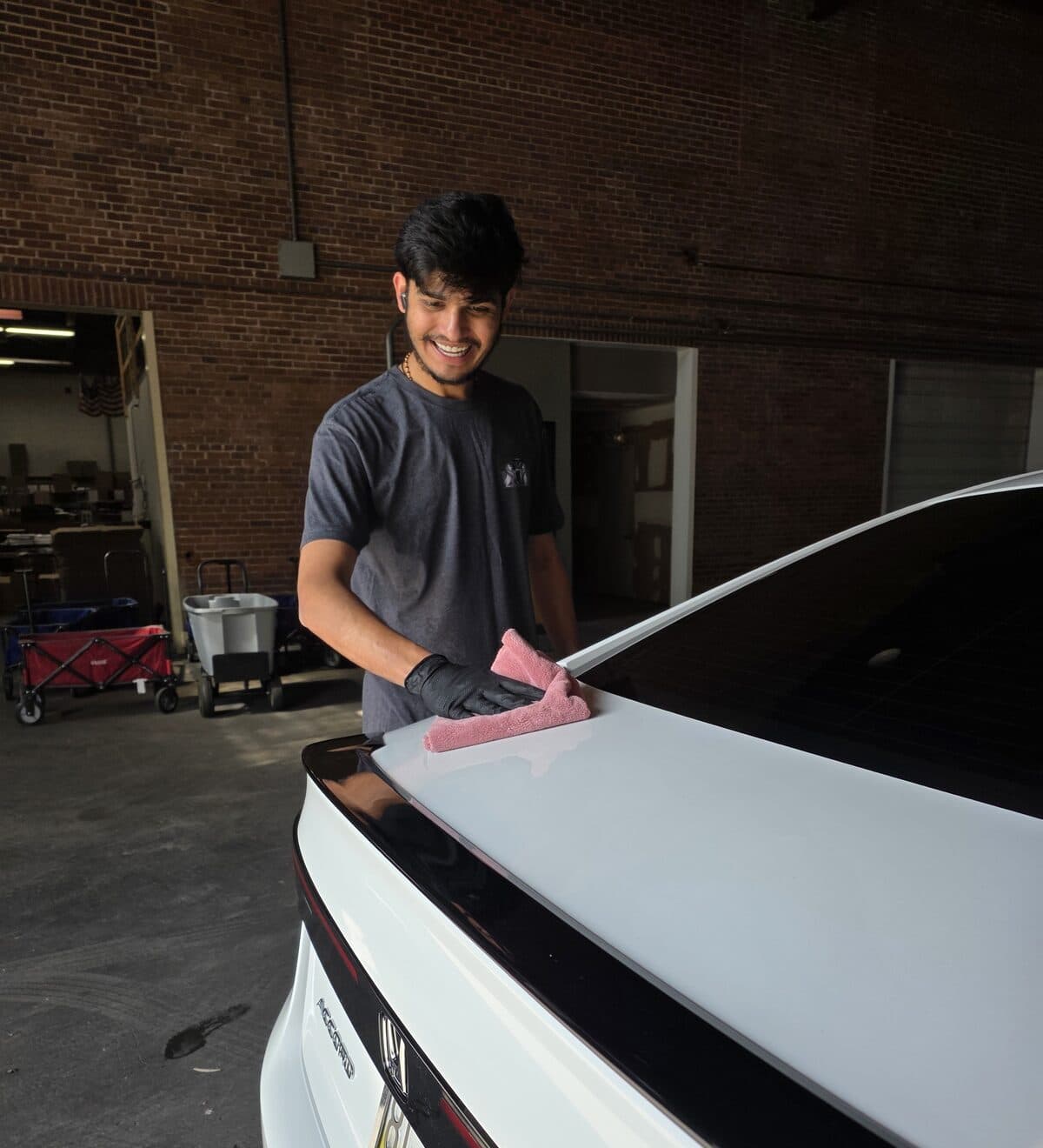 Mr. G hand drying the glossy decklid of a freshly detailed white Honda in the Mr. G's Auto Care shop in Westminster, MD