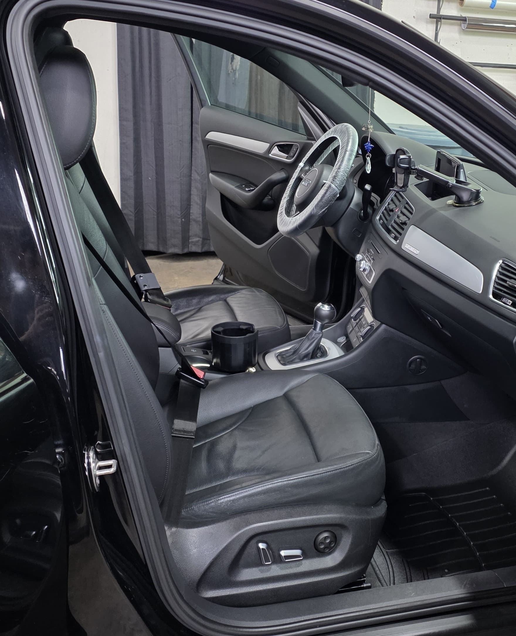 The clean black leather front cabin and floor of an Audi Q3 after a full interior detail at Mr. G's Auto Care in Westminster, MD
