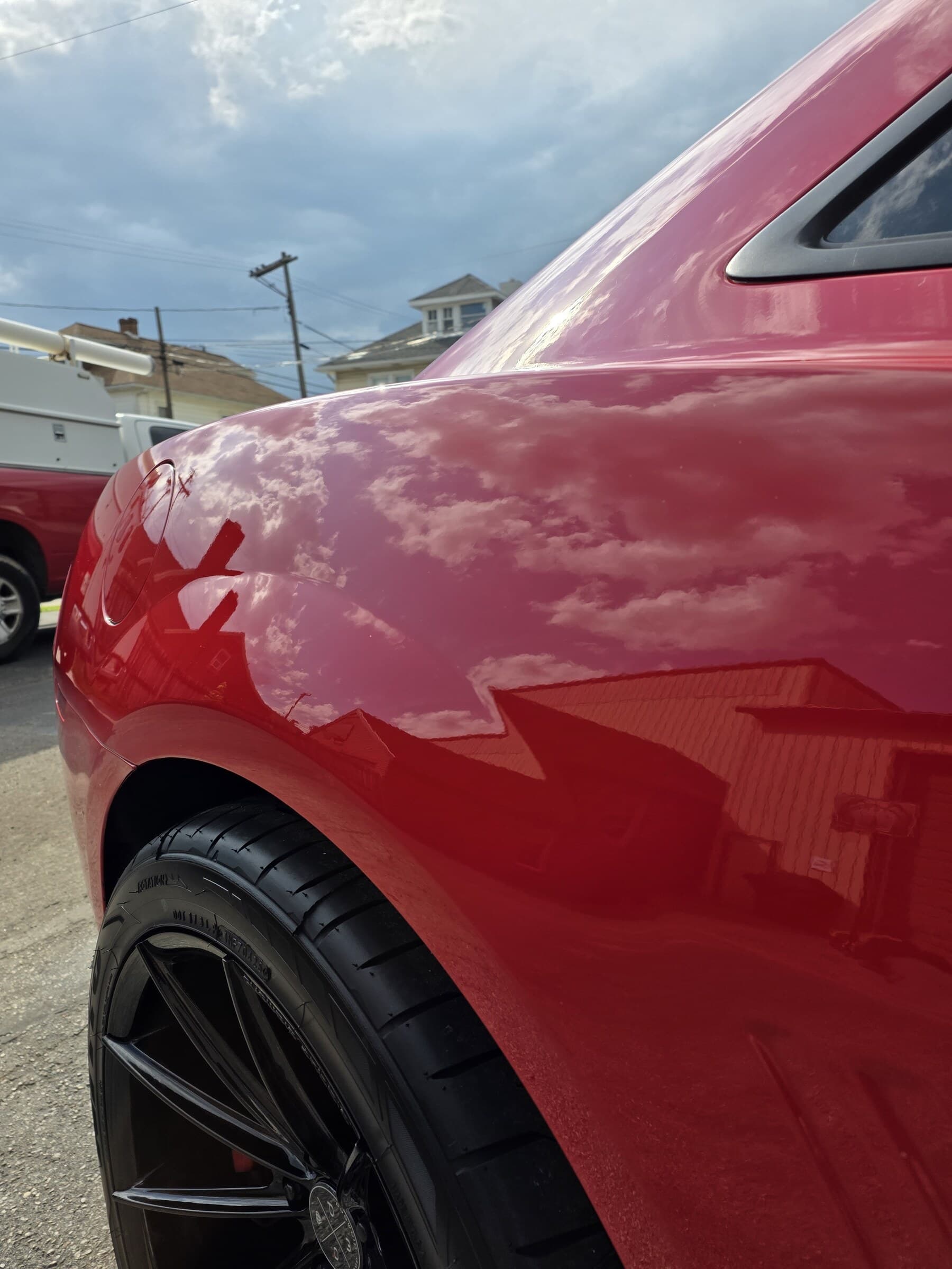 The mirror finish on the red quarter panel of a Chevrolet Camaro reflecting the sky after paint correction in Westminster, MD