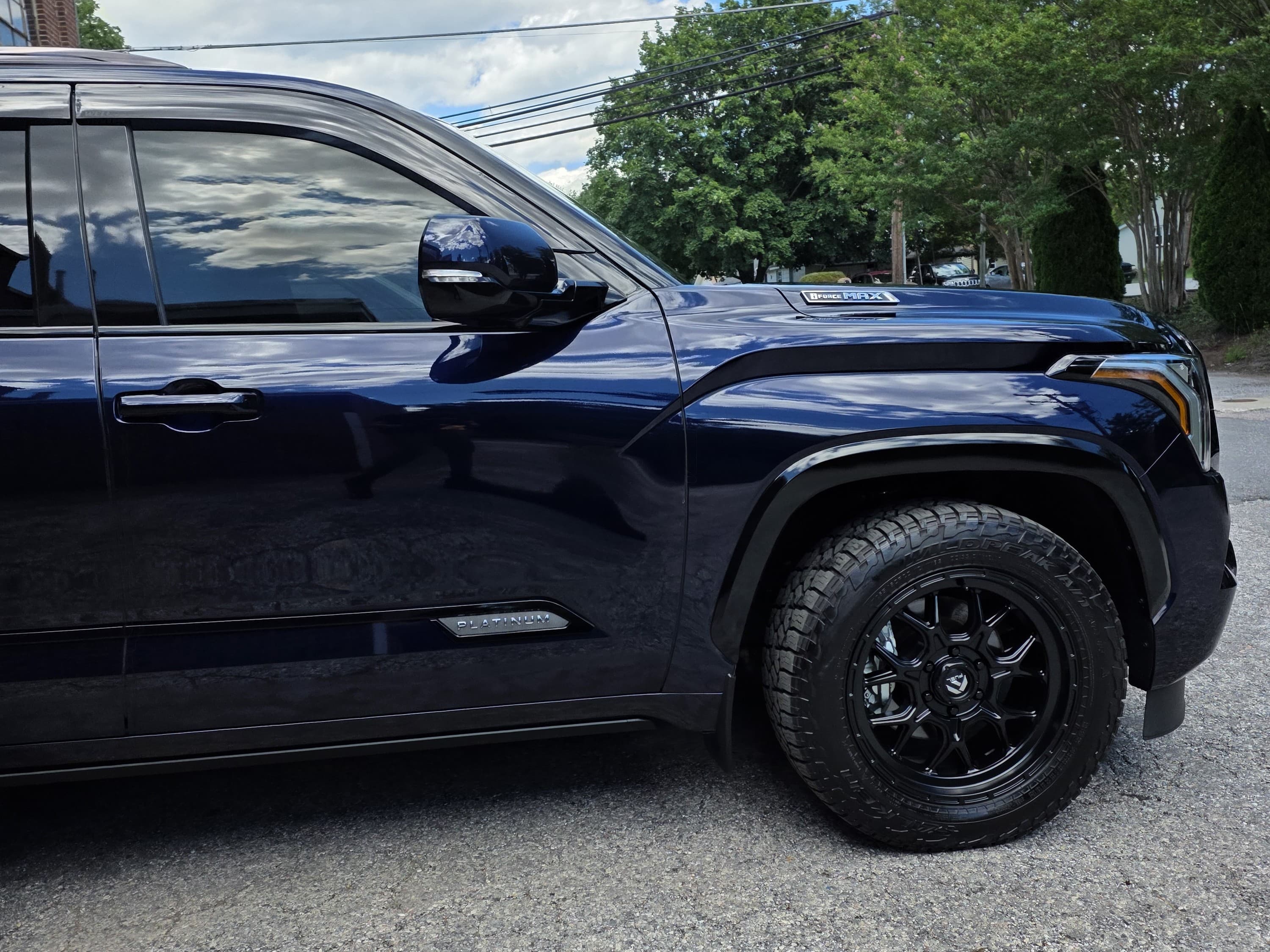 The glossy front quarter of a navy Toyota Sequoia after a full exterior detail, photographed outdoors in Carroll County, MD