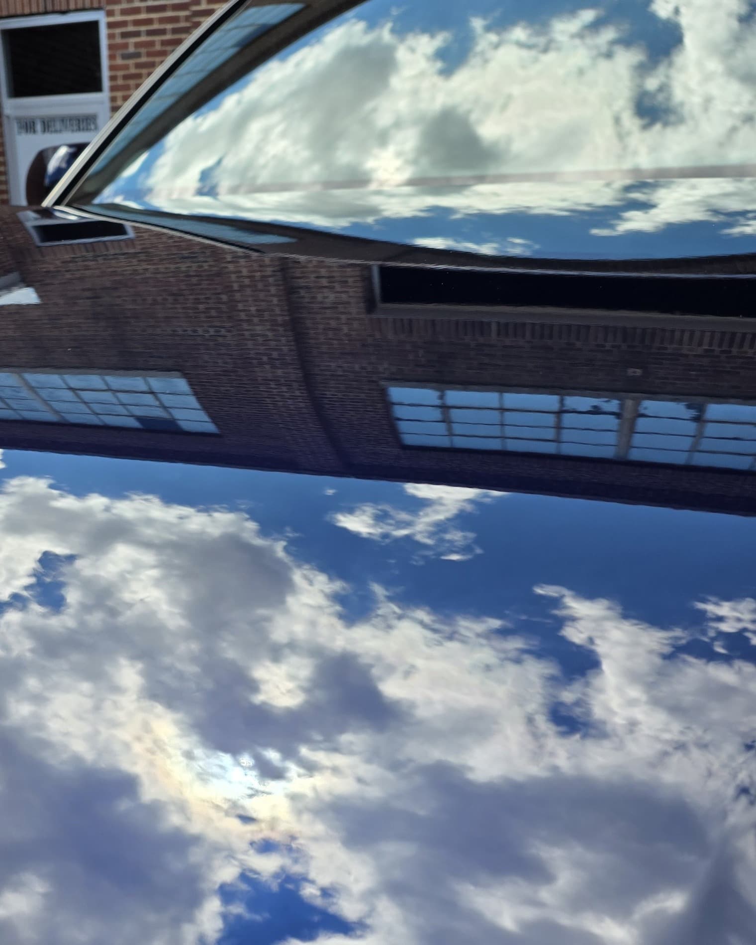 Sky and clouds reflecting in the deep, mirror-flat ceramic coated paint of a Toyota Sequoia at Mr. G's Auto Care in Westminster, MD