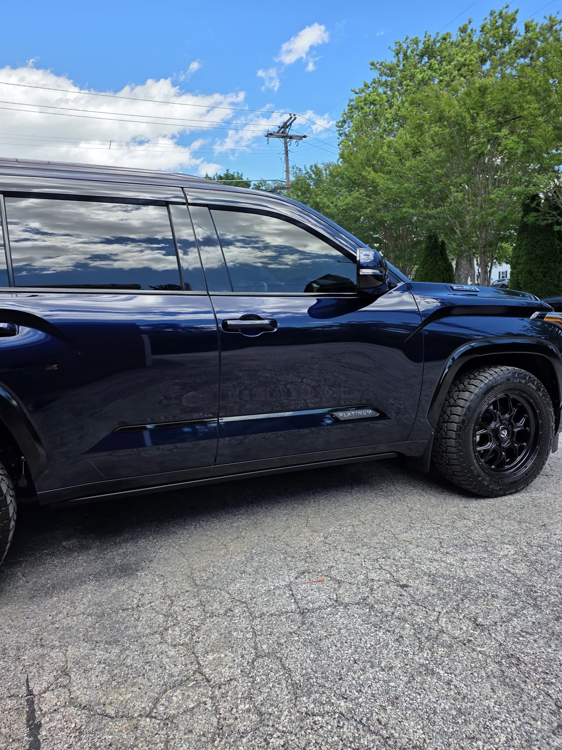 A dark blue Toyota Sequoia with a deep ceramic coated gloss reflecting the sky, photographed outdoors in Carroll County, MD